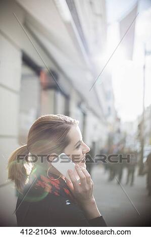 Stock Image - Woman talking on cell phone on city street. Fotosearch