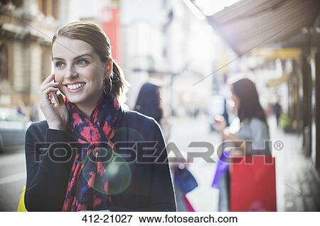 Woman talking on cell phone on city street View Large Photo Image Stock Photo - Woman talking on cell phone on city street . Fotosearch