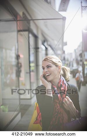 Woman talking on cell phone while walking down city street View Large Photo Image Stock Photo - Woman talking on cell phone while walking down city street. Fotosearch