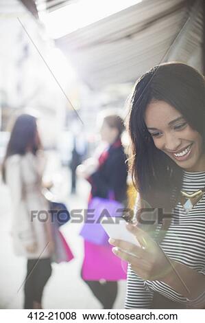 Woman using cell phone on city street View Large Photo Image Stock Photo - Woman using cell phone on city street . Fotosearch
