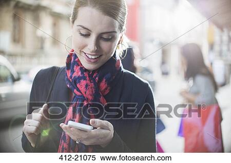 Woman using cell phone on city street View Large Photo Image Stock Photography - Woman using cell phone on city street. Fotosearch