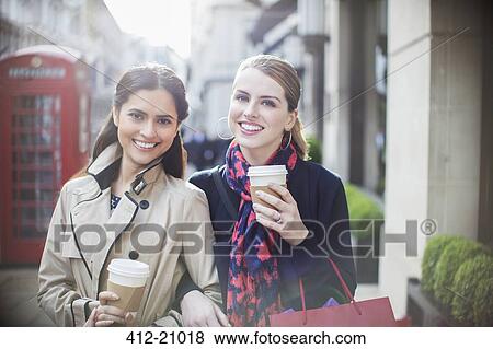 Women drinking coffee together down city street View Large Photo Image Stock Photo - Women drinking coffee together down city street. Fotosearch