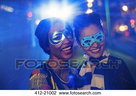 Stock Image - Women in masks smiling together. Fotosearch