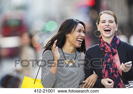 Women laughing together walking down city street View Large Photo Image Stock Image - Women laughing together walking down city street . Fotosearch