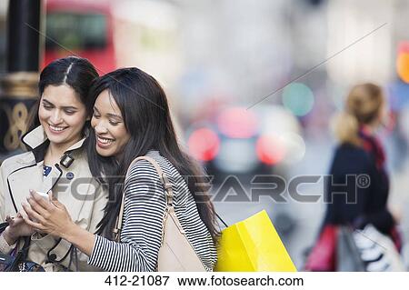 Stock Photo - Women looking at cell phone on city street. Fotosearch