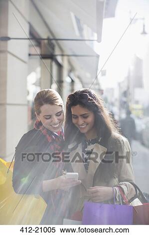 Women looking at cell phone together on city street View Large Photo Image Stock Photography - Women looking at cell phone together on city street . Fotosearch