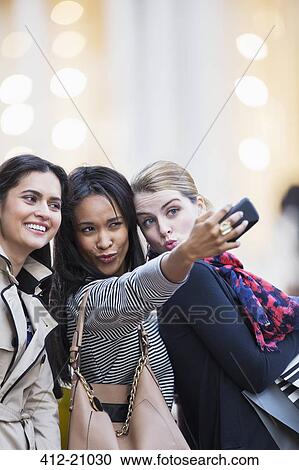 Stock Image - Women taking cell phone picture together. Fotosearch