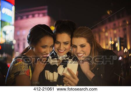 Women talking picture together on city street at night View Large Photo Image Stock Image - Women talking picture together on city street at night. Fotosearch