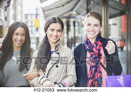 Stock Image - Women walking down city street together. Fotosearch