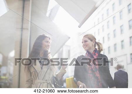 Stock Image - Women walking down city street together. Fotosearch