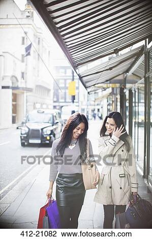 Stock Image - Women walking down city street together. Fotosearch