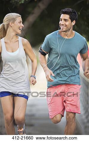 Stock Image - Couple running through city streets together. Fotosearch