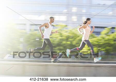 Couple running through city streets together View Large Photo Image Stock Photo - Couple running through city streets together. Fotosearch
