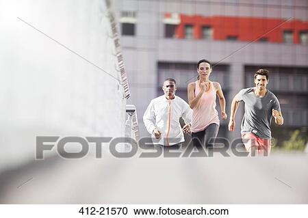 Stock Image - Friends running through city streets together. Fotosearch