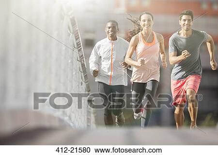 Stock Image - Friends running through city streets together . Fotosearch