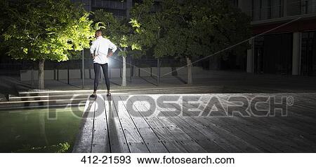 Stock Image - Man standing in park at night. Fotosearch