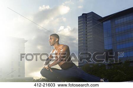 Stock Image - Man stretching before exercising on city street. Fotosearch