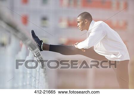 Man stretching before exercising on city street View Large Photo Image Stock Photography - Man stretching before exercising on city street. Fotosearch