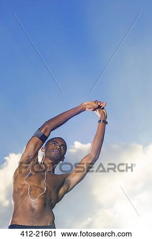 Stock Image - Man stretching before exercising outdoors. Fotosearch