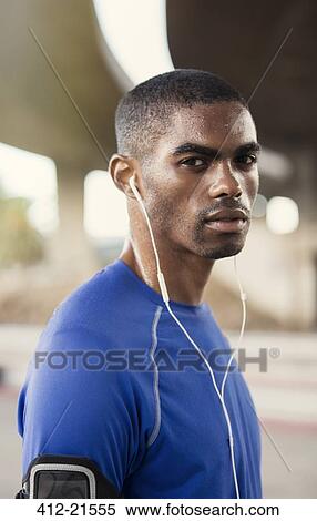 Man with headphones exercising on city street View Large Photo Image Stock Photography - Man with headphones exercising on city street. Fotosearch