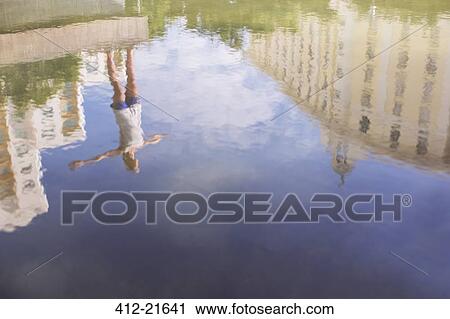 Stock Image - Reflection of woman stretching in city park. Fotosearch