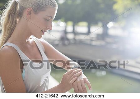 Woman looking at watch before exercising on city street View Large Photo Image Stock Image - Woman looking at watch before exercising on city street. Fotosearch