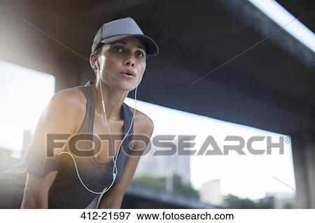 Stock Photo - Woman resting after exercising on city street. Fotosearch