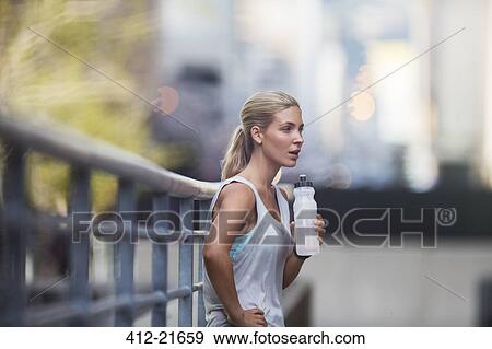 Woman resting after exercising on city street View Large Photo Image Stock Photo - Woman resting after exercising on city street. Fotosearch