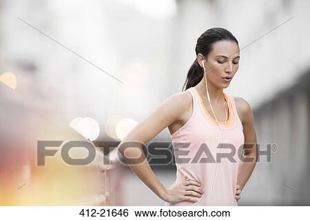 Stock Photograph - Woman resting after exercising on city street. Fotosearch