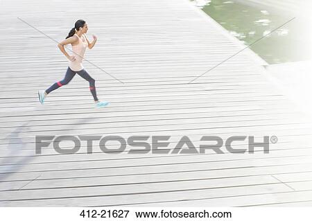 Woman running through city streets View Large Photo Image Stock Photo - Woman running through city streets. Fotosearch