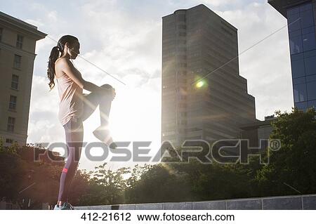 Stock Image - Woman stretching before exercising on city street. Fotosearch