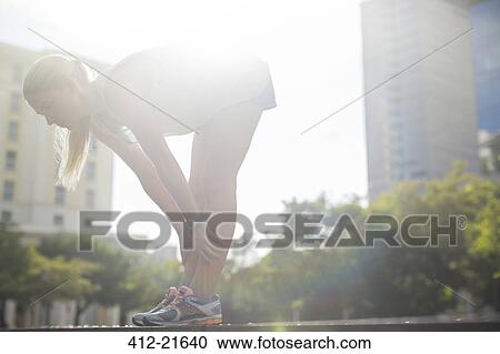 Stock Image - Woman stretching before exercising on city street. Fotosearch