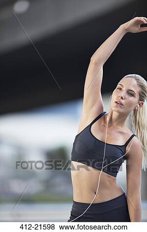 Stock Photo - Woman stretching before exercising on city street. Fotosearch