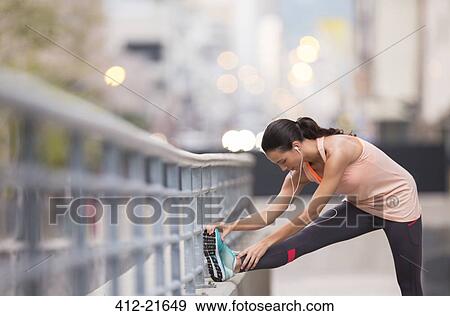 Woman stretching before exercising on city street View Large Photo Image Stock Photo - Woman stretching before exercising on city street. Fotosearch