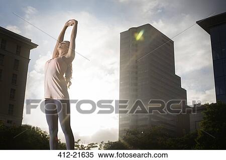 Stock Photography - Woman stretching before exercising on city street. Fotosearch