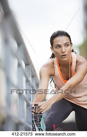 Stock Image - Woman stretching her legs before exercise. Fotosearch