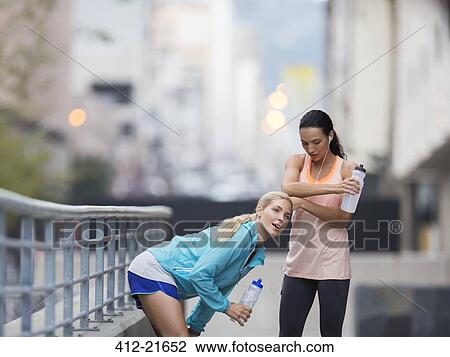 Stock Image - Women resting after exercising on city street. Fotosearch