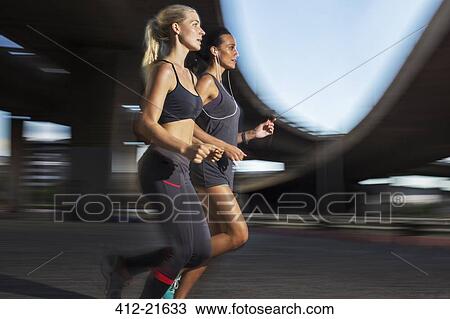 Stock Image - Women running together through city streets. Fotosearch