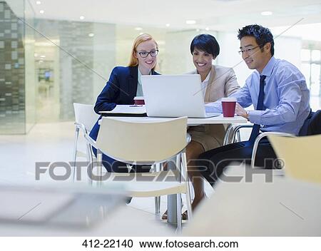 Business people gathered around laptop in office building cafe View Large Photo Image Stock Image - Business people gathered around laptop in office building cafe. Fotosearch