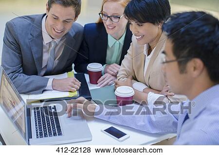Business people gathered around laptop in office building cafe View Large Photo Image Stock Photo - Business people gathered around laptop in office building cafe . Fotosearch