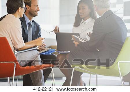 Stock Image - Business people having meeting in office building. Fotosearch