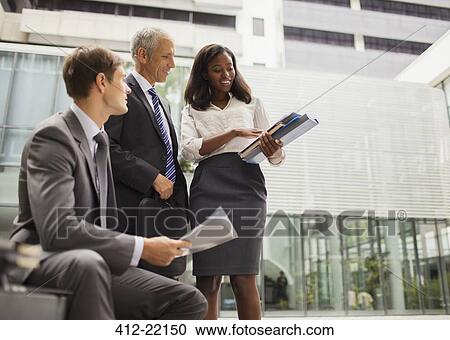 Stock Image - Business people looking at documents in office building. Fotosearch