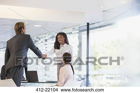 Picture - Business people shaking hands in office building. Fotosearch