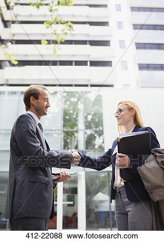Business people shaking hands outside of office building View Large Photo Image Stock Photo - Business people shaking hands outside of office building. Fotosearch