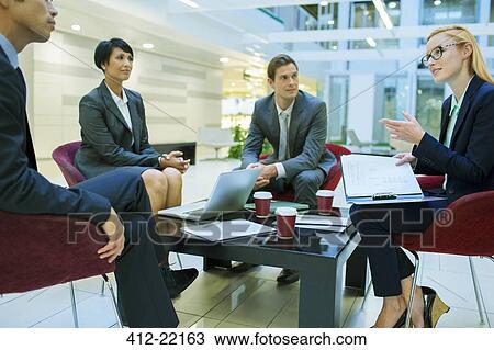 Stock Image - Business people talking in meeting in office building. Fotosearch