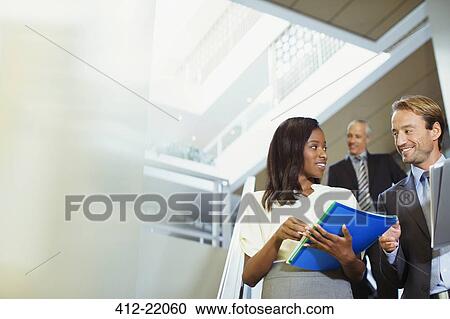 Stock Image - Business people talking in office building. Fotosearch