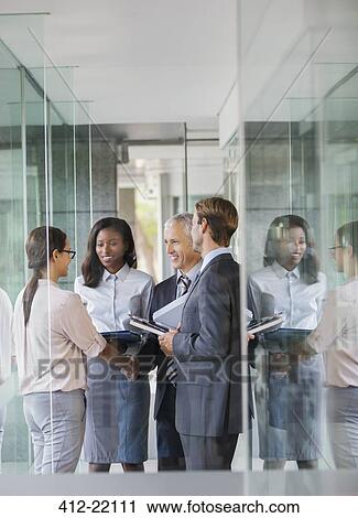 Stock Image - Business people talking in office building. Fotosearch