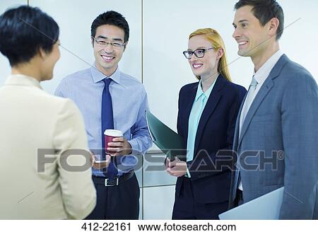 Stock Image - Business people talking in office building. Fotosearch