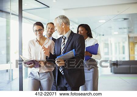 Stock Image - Business people walking and talking in office. Fotosearch