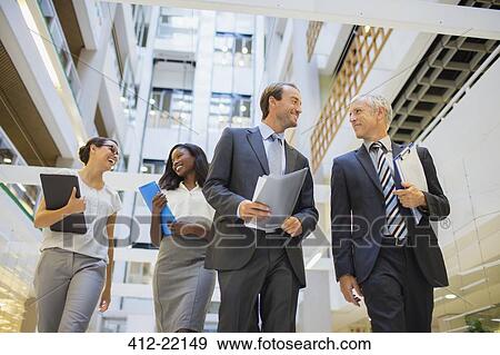 Stock Photo - Business people walking together in office building. Fotosearch